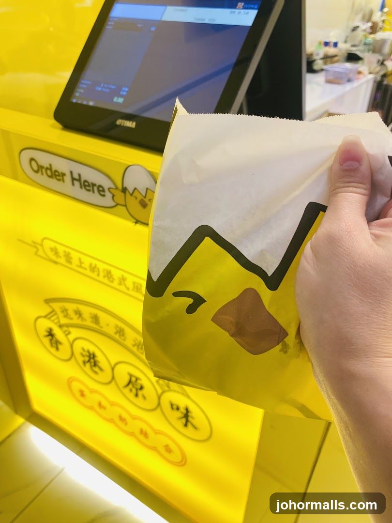 Hand holding packaged food in front of yellow counter