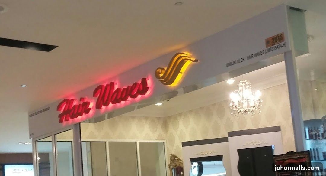 Storefront with illuminated red neon sign reading 'Hair Waves' and a golden wave logo above it. The entrance features glass doors and a chandelier hanging inside the salon. A small plaque on the upper right indicates 'DILIKU OLEH: HAIR WAVES (L0315434-H)' and a 2016 date marker. Interior walls have patterned wallpaper, and part of an interior display or counter is visible.