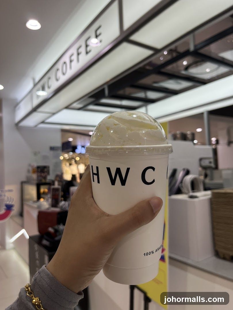 Hand holding a coffee cup with whipped cream