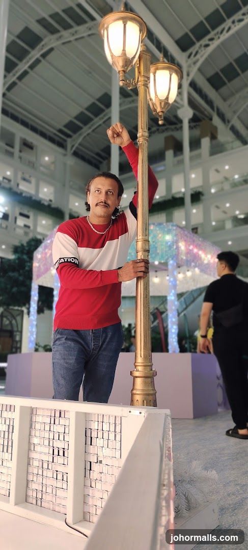 Man posing by a lamppost in a mall