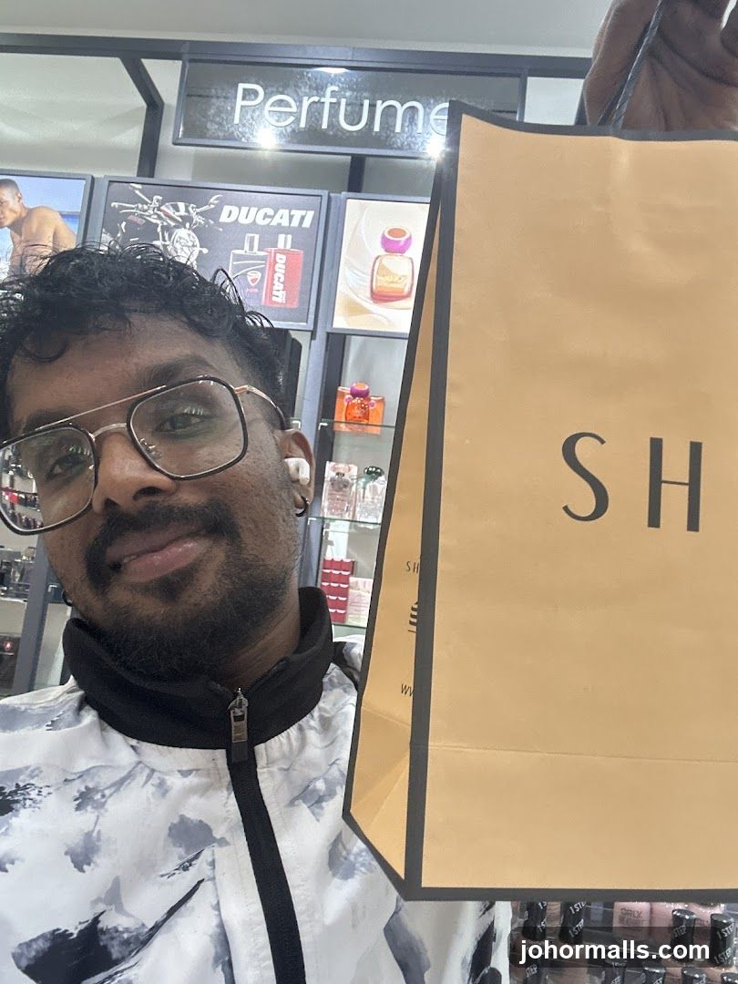 Man holding a shopping bag in a perfume store