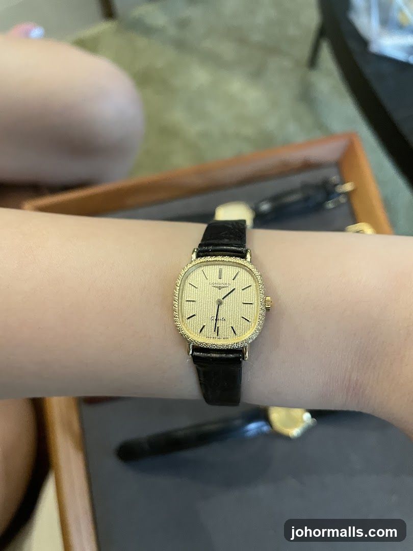 Gold watch with black band on wrist