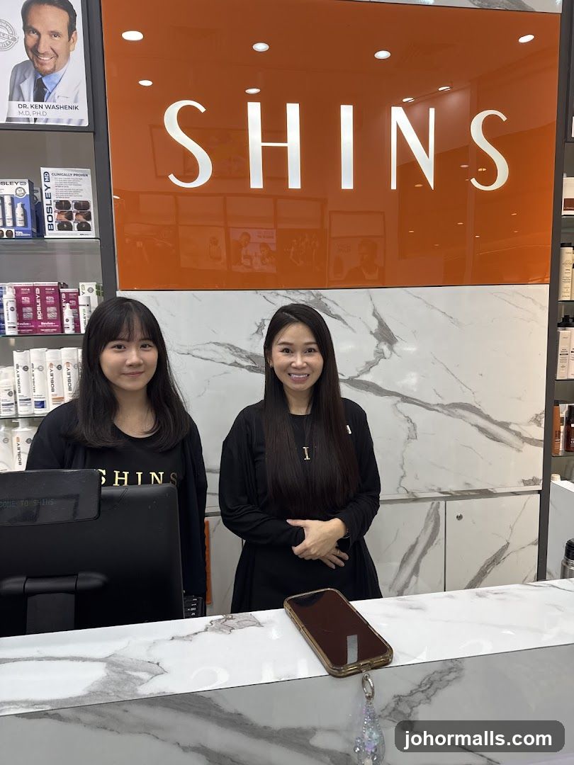 Two women standing behind a counter with a sign that says SHINS