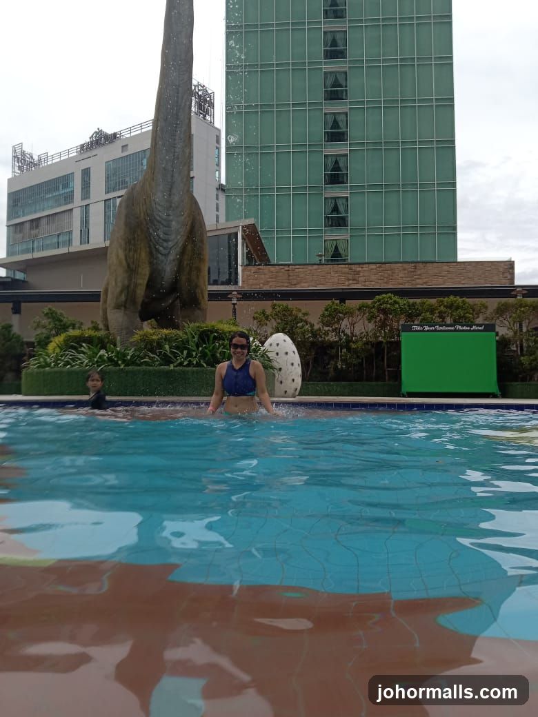 People Swimming Near Dinosaur Statue and Hotel