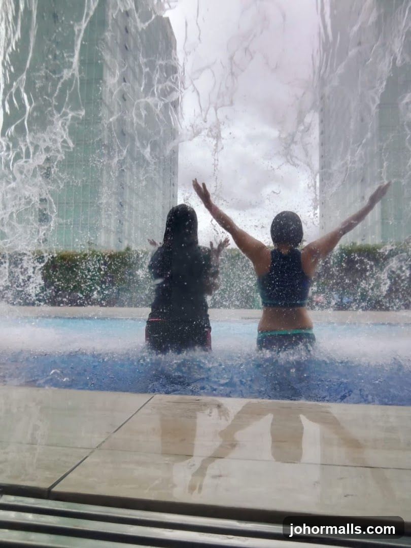 People Enjoying a Waterfall Feature at a Pool