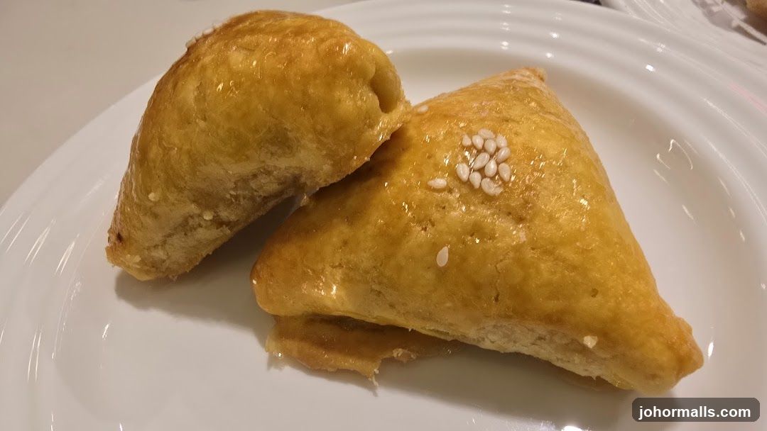 Two Golden Pastries on a White Plate