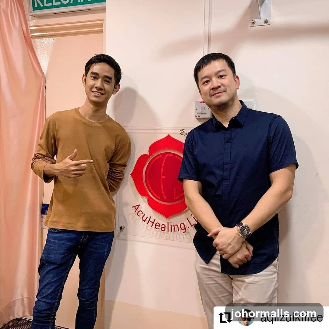 Two Men Posing by a Logo