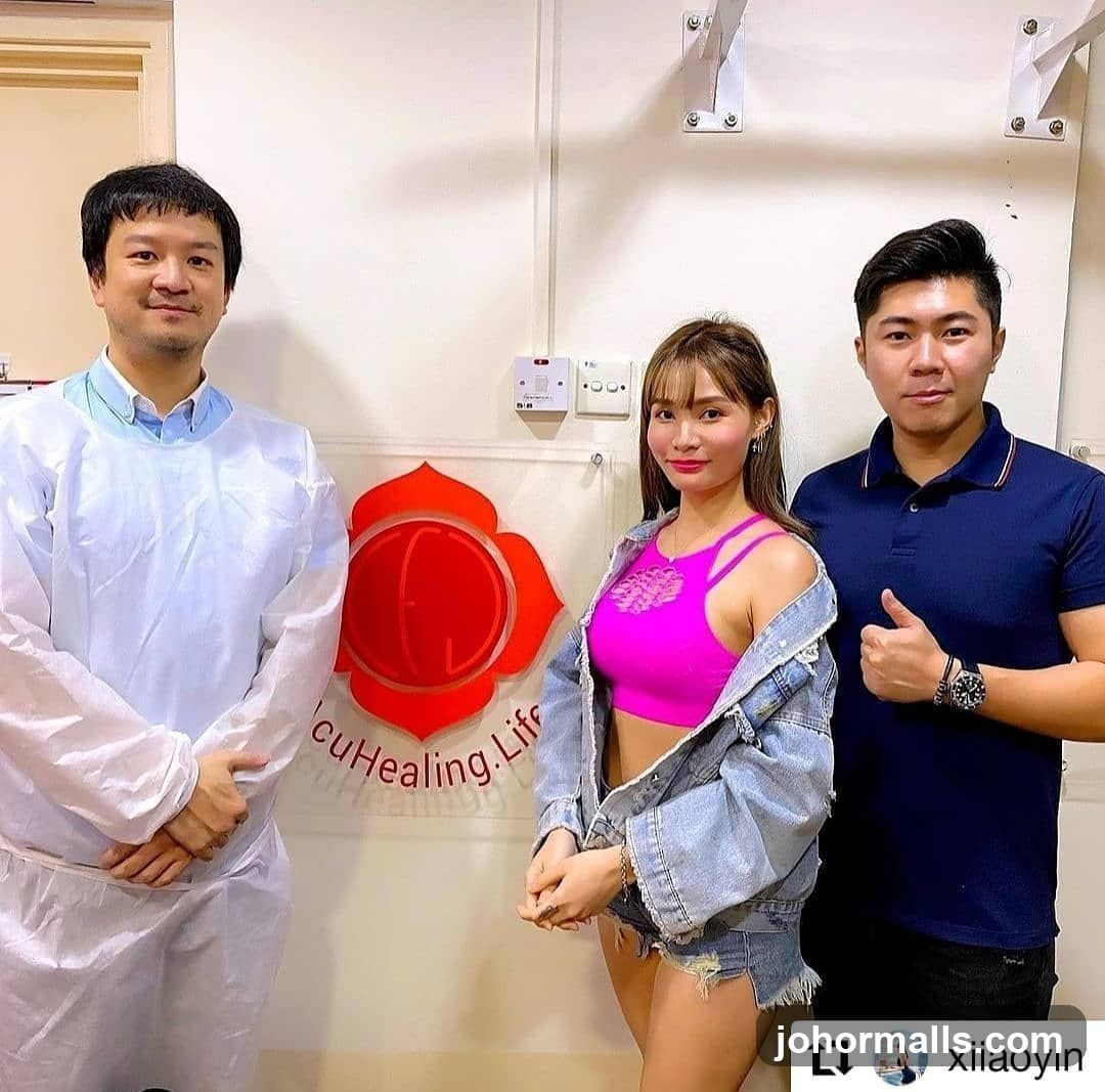 Three people posing in front of a logo
