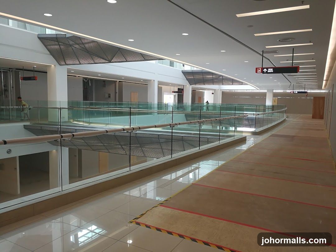 Interior of a modern shopping mall with glass railings and directional signs.