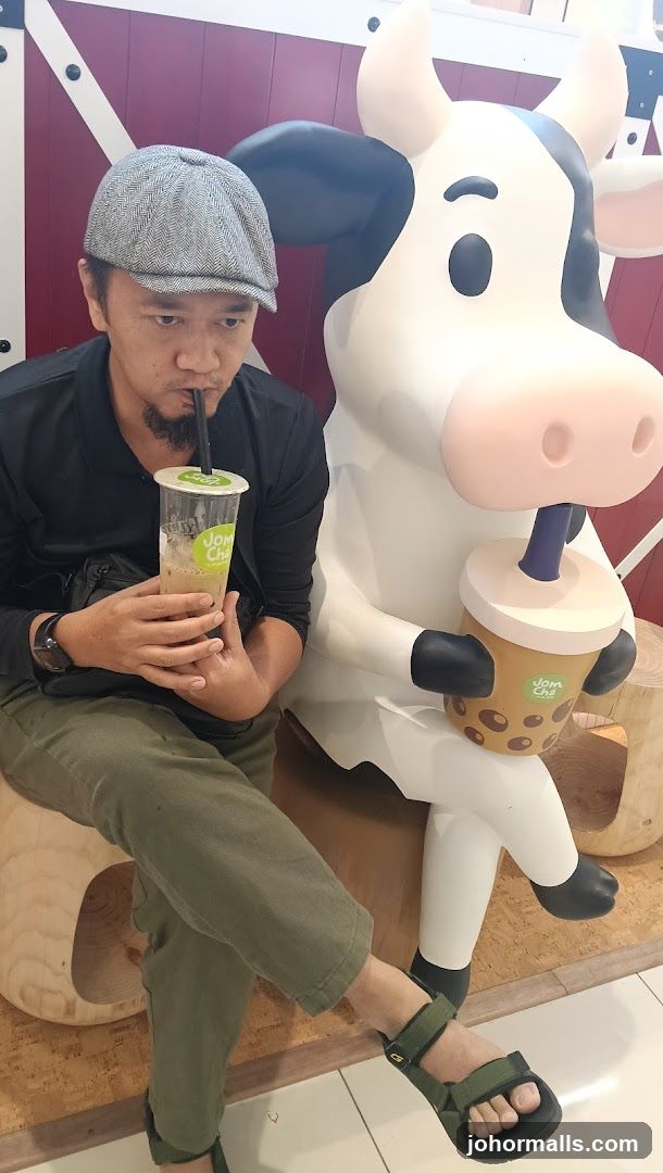 Man drinking bubble tea next to a cow statue
