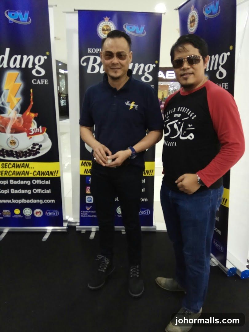 Two men posing in front of promotional banners