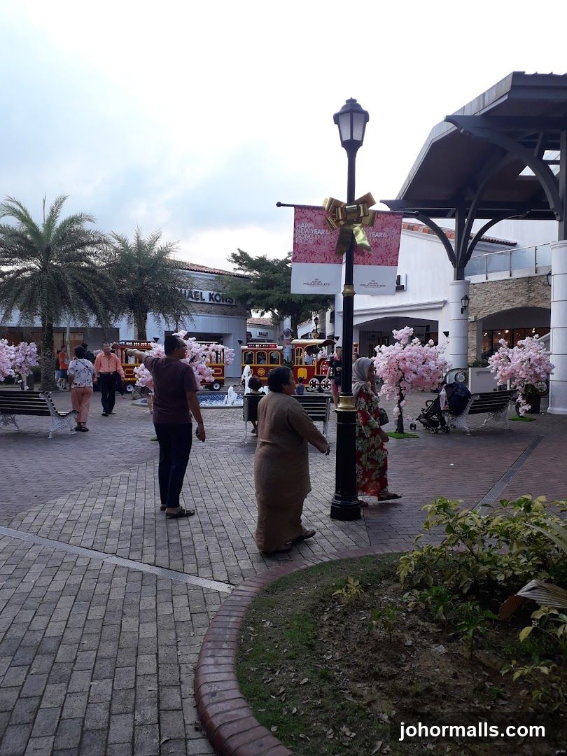 Outdoor shopping area with decorative trees and a train