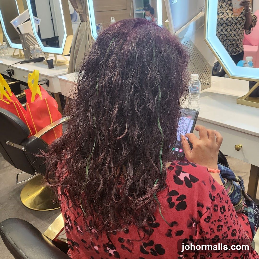 Woman with long, curly, dark hair with green streaks
