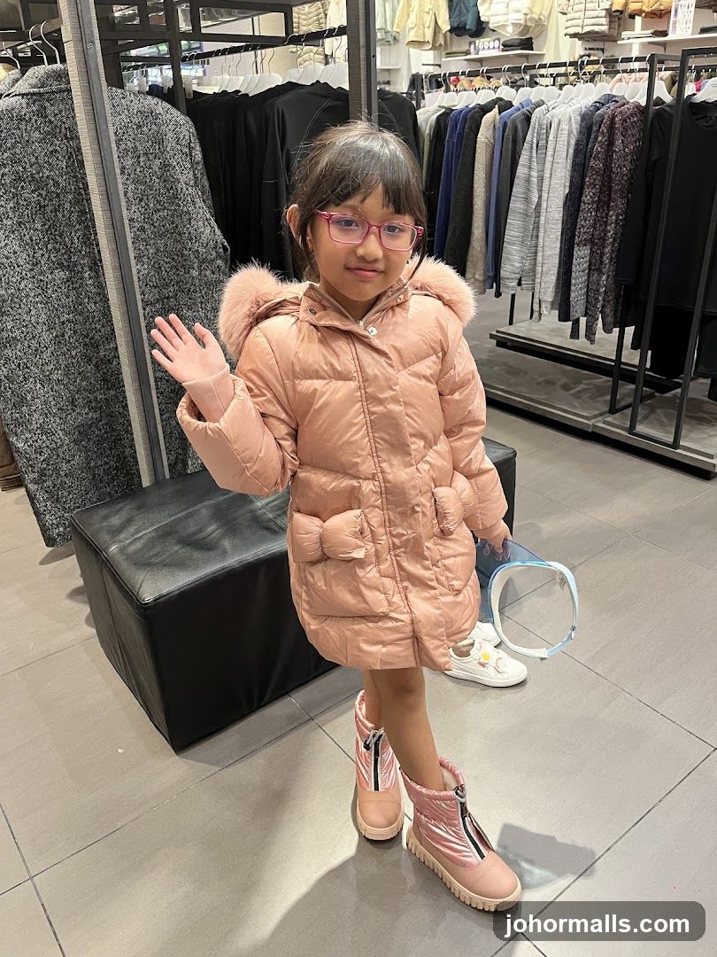 Girl in a pink puffer coat and boots in a clothing store