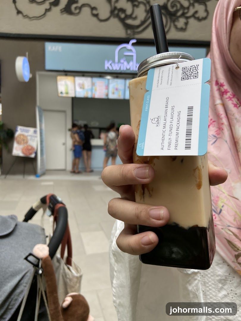 Person holding a drink in front of a cafe