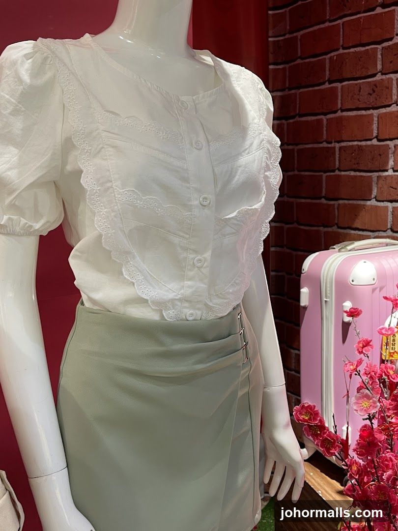 Mannequin wearing a white blouse and green skirt