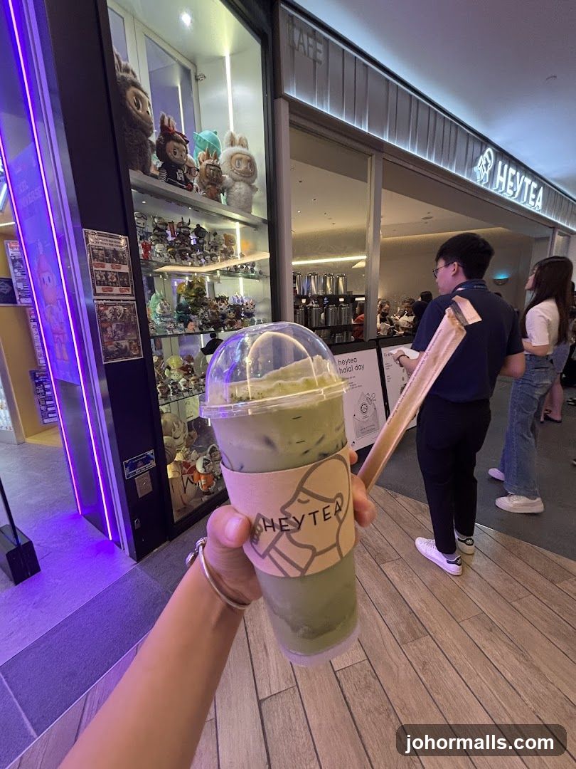 Person holding a matcha drink in front of a cafe