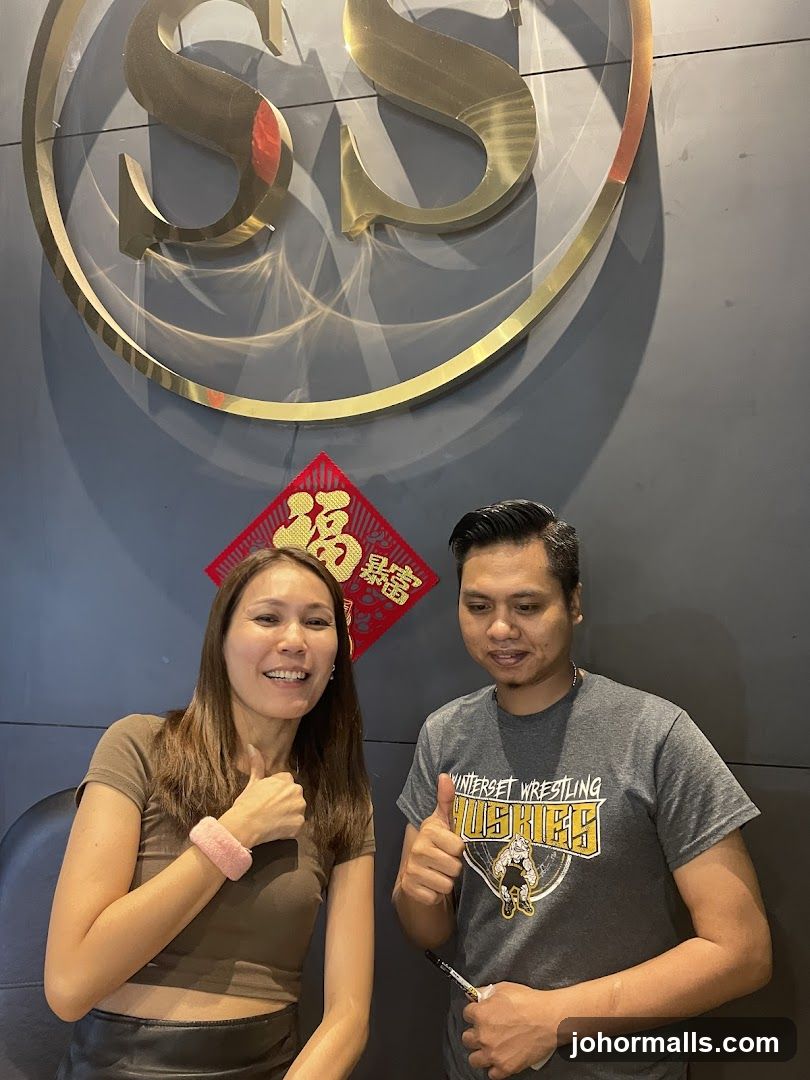 Two people posing in front of a logo