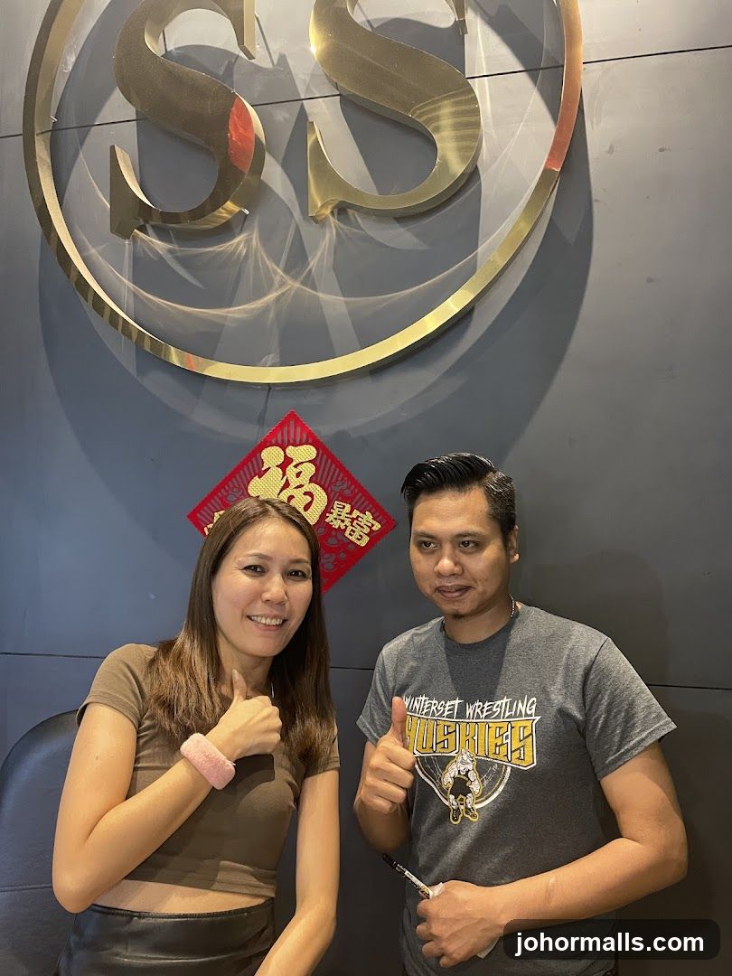 Two people posing in front of a logo