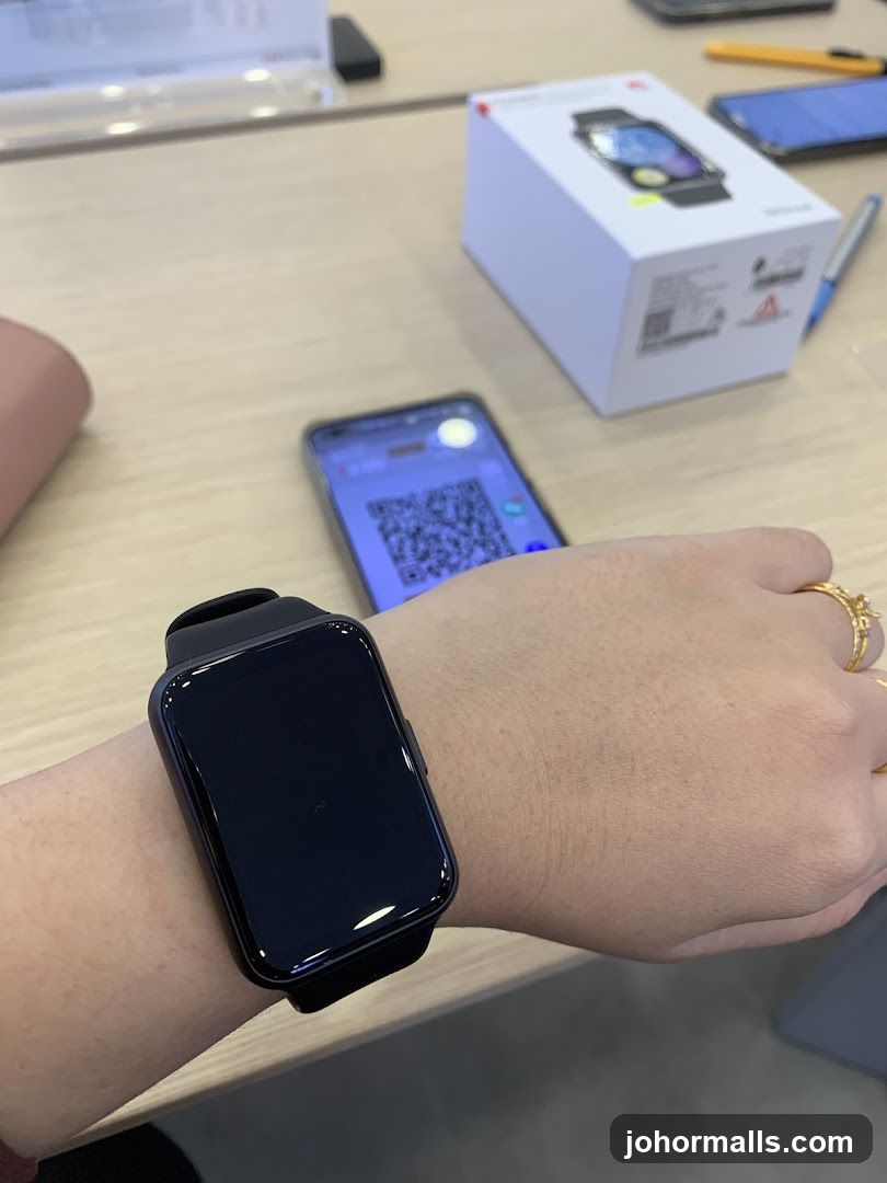 Smartwatch on wrist with product box and phone