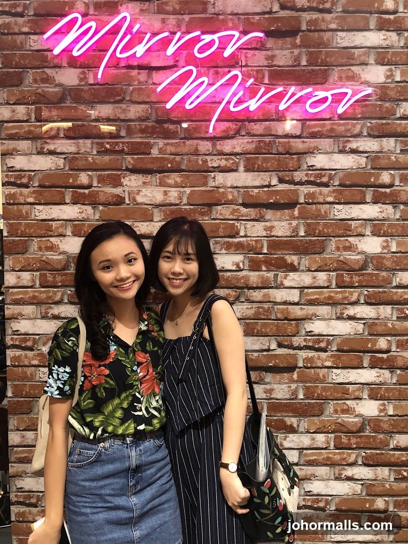 Two Women Posing in Front of Neon Sign