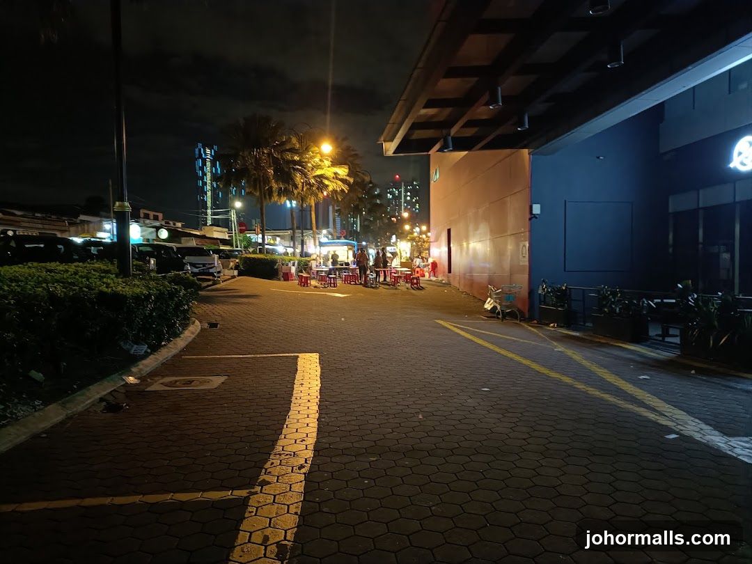 Nighttime street scene with food stalls and modern building