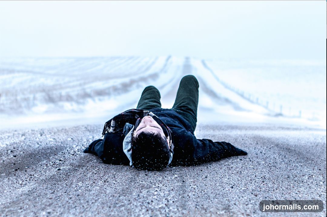 Person lying on a snowy road