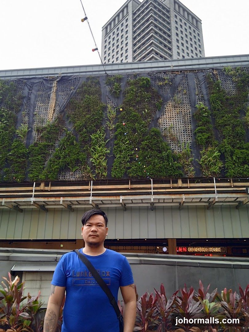 Man in front of a building with a vertical garden