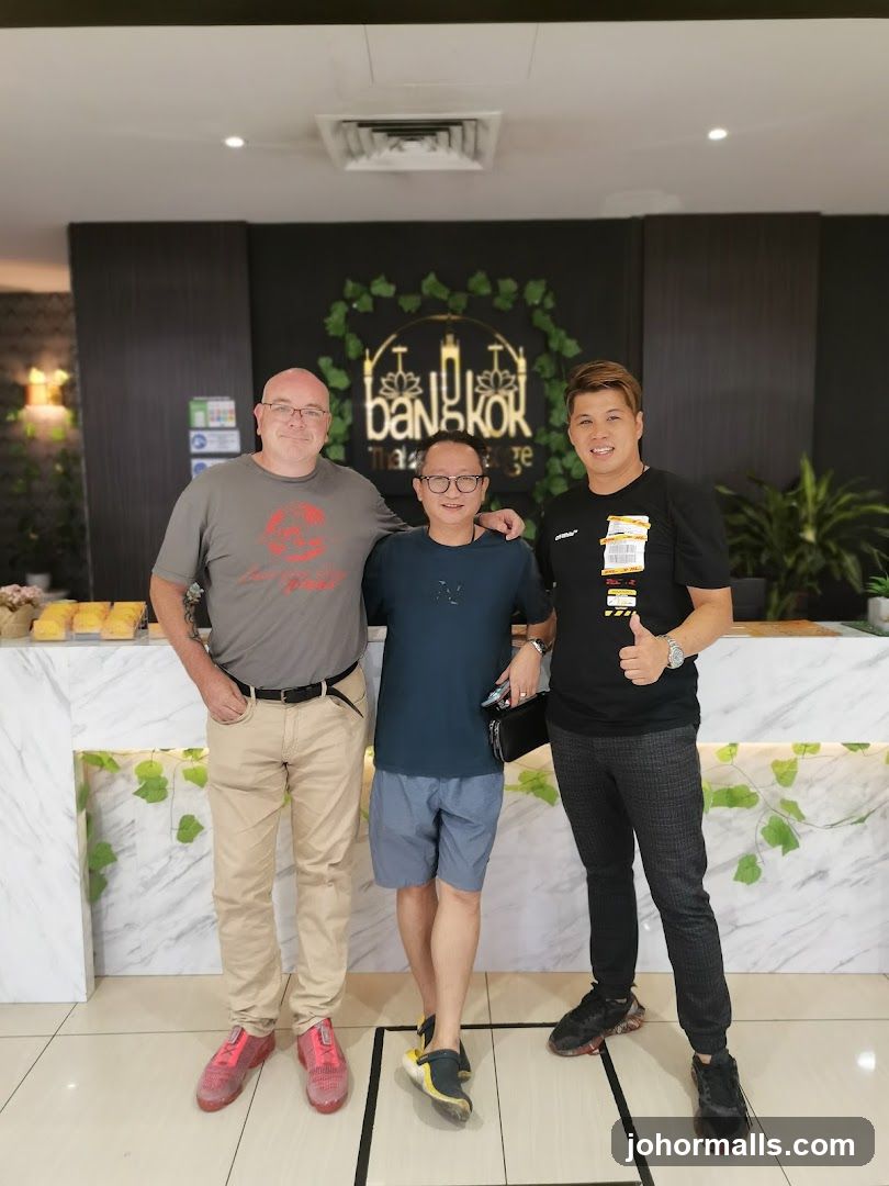 Three men posing in front of a massage parlor sign