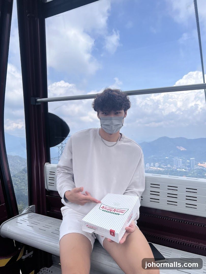 Man holding Krispy Kreme box in cable car