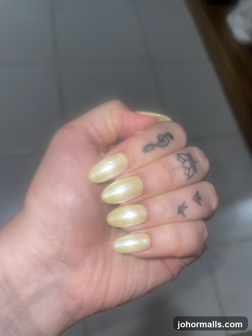 Hand with light yellow nails and tattoos