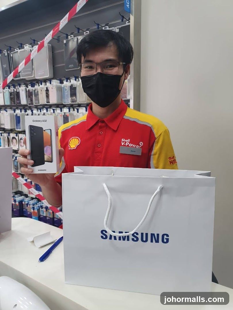 Employee holding a Samsung Galaxy A32 box and a Samsung shopping bag