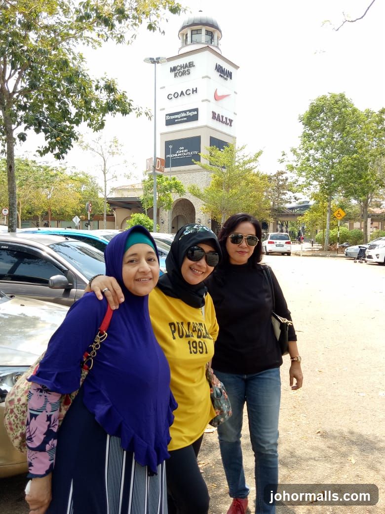 Three Women Posing in Front of an Outlet Mall Tower