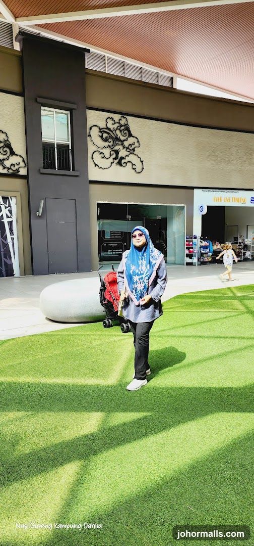Woman in a blue hijab and patterned shirt standing on artificial grass