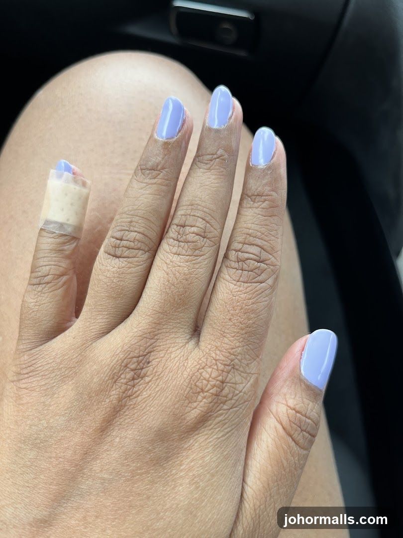 Fingernails with light purple polish and a band-aid