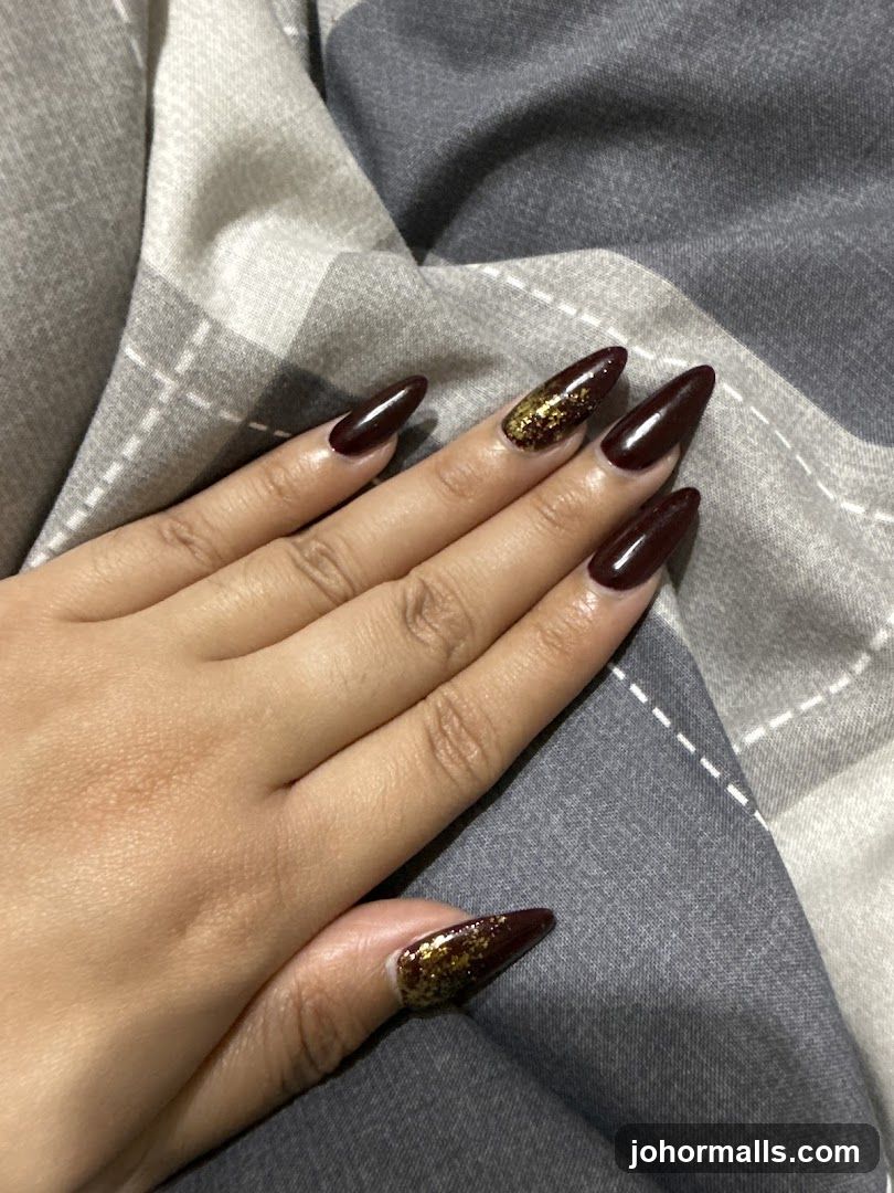 Hand with Burgundy and Gold Glitter Nails