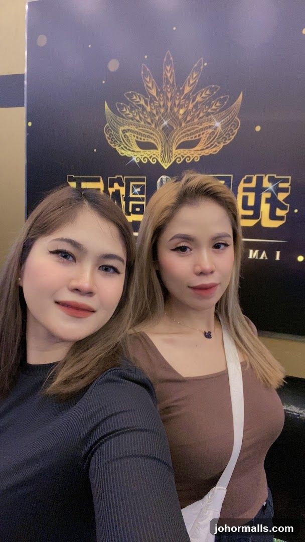 Two women posing in front of a promotional backdrop