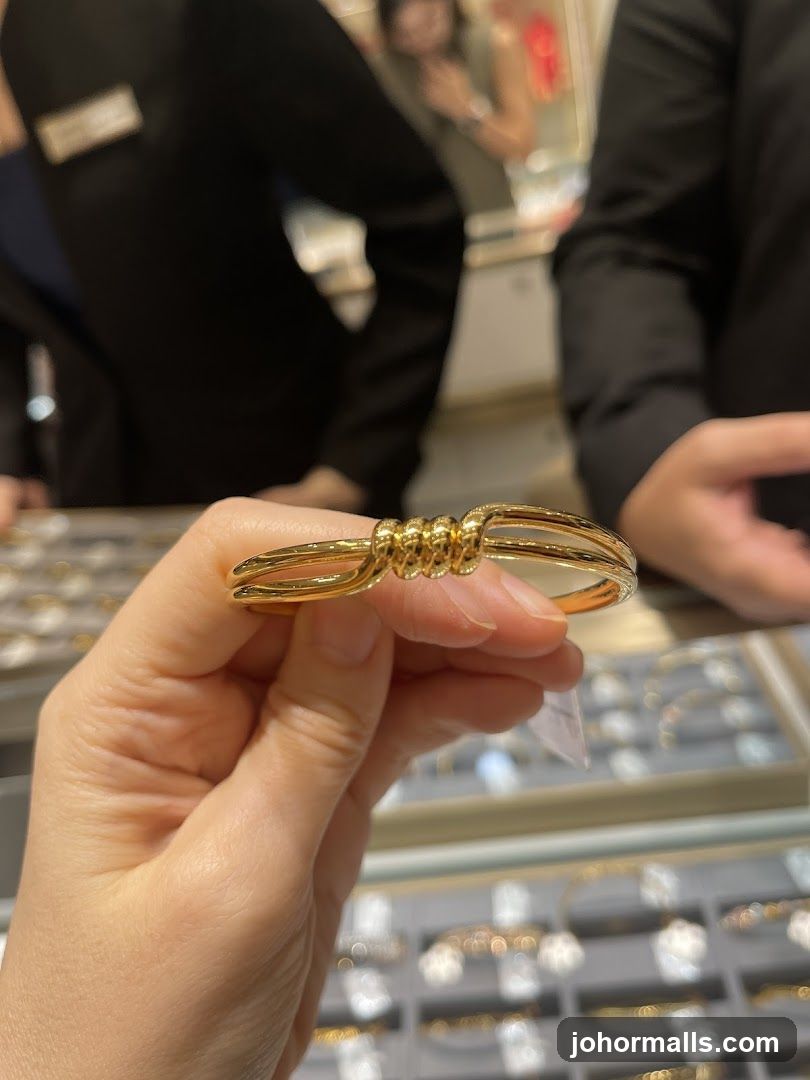 Hand holding a gold bracelet in a jewelry store