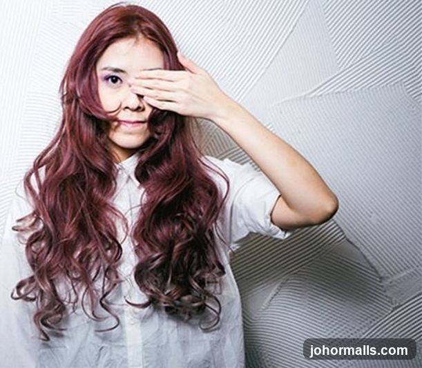 Woman with long, wavy, burgundy hair covering one eye