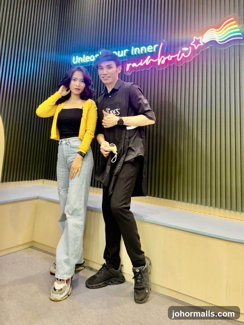 Two people posing in front of a neon sign