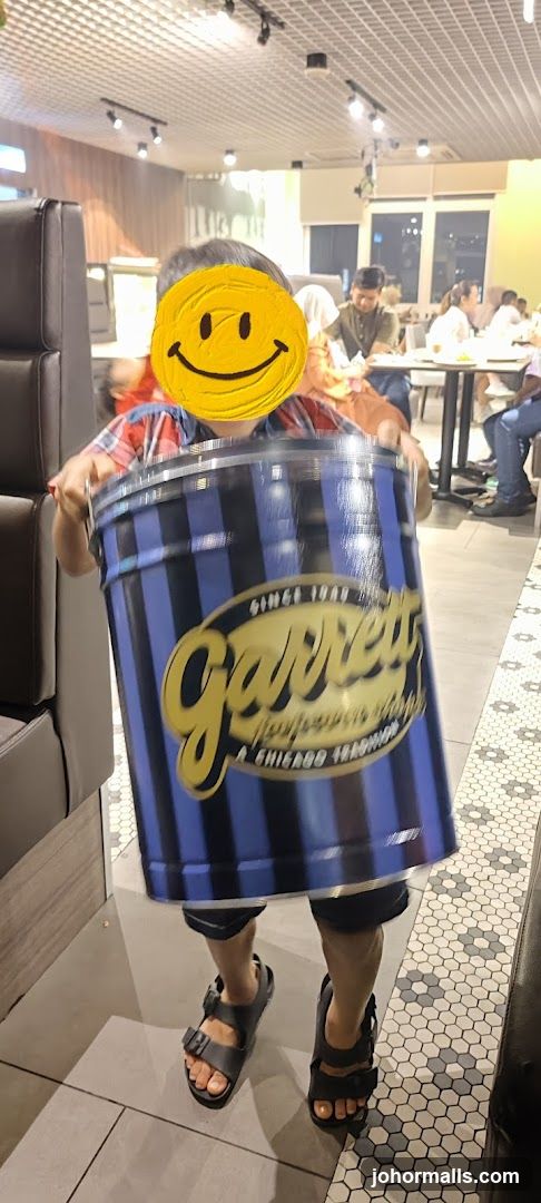 Person holding a large tin can with Garrett Popcorn logo