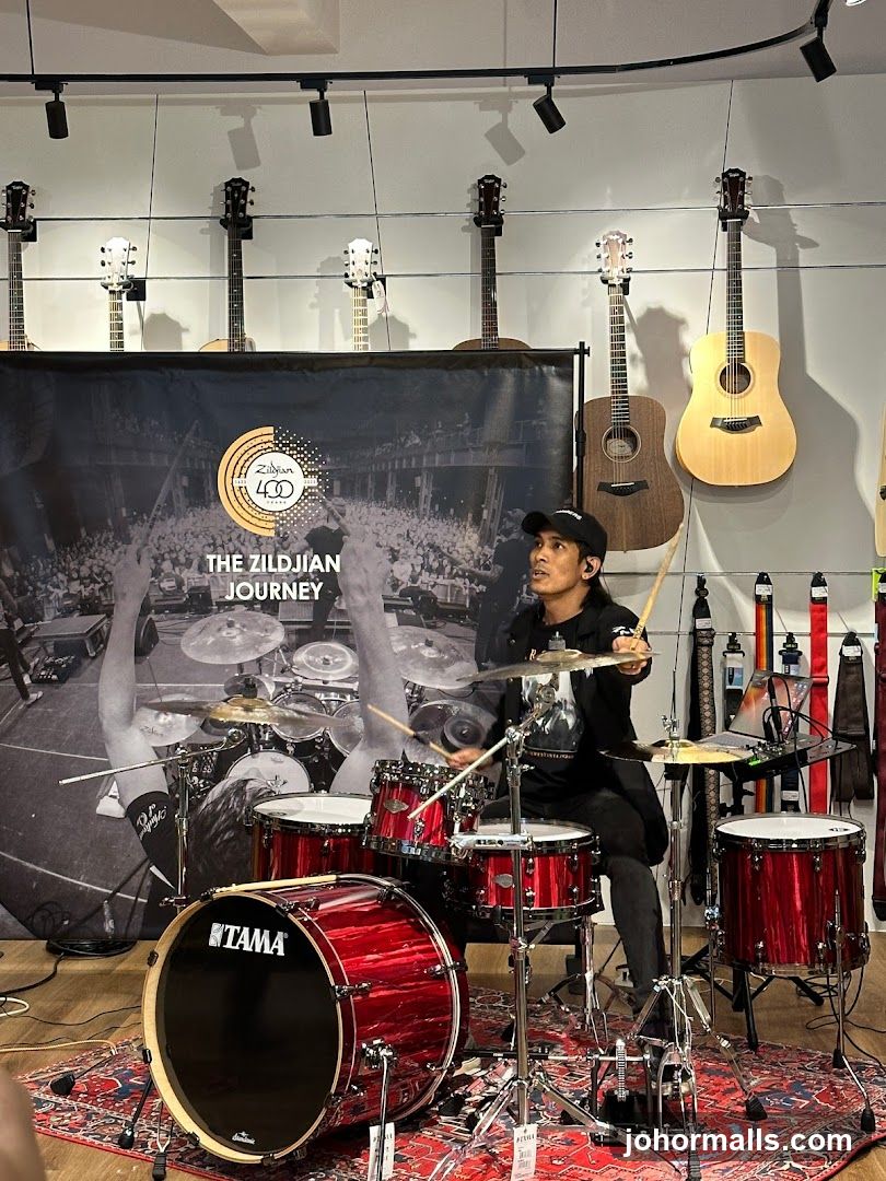 Drummer playing a red drum set in a music store