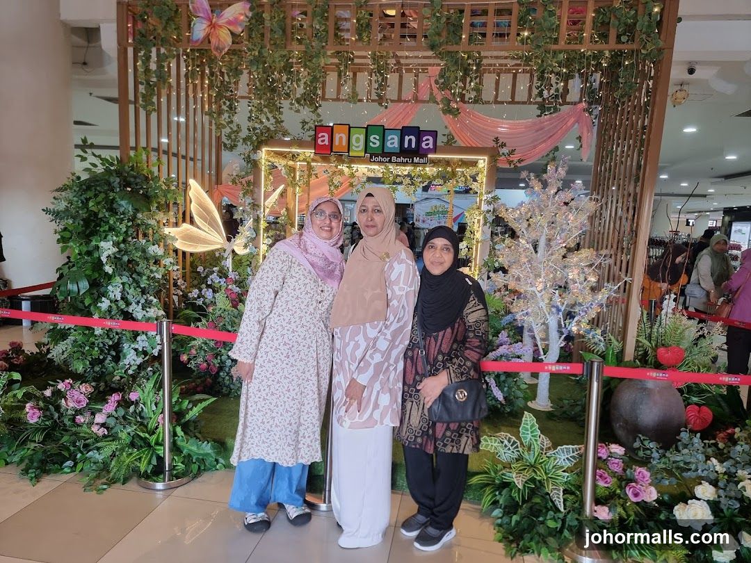 Three women posing in front of a decorative display