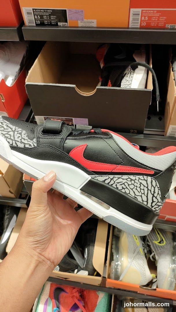 Hand holding a black and red Nike sneaker