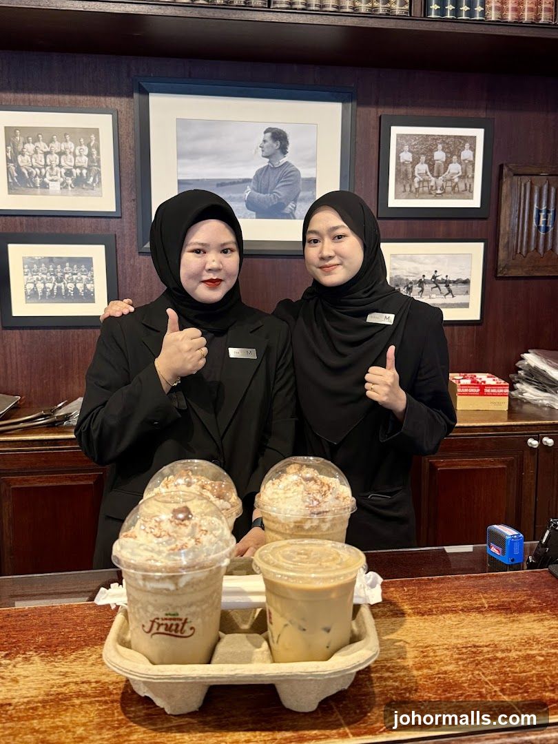 Two women in black uniforms giving thumbs up with drinks