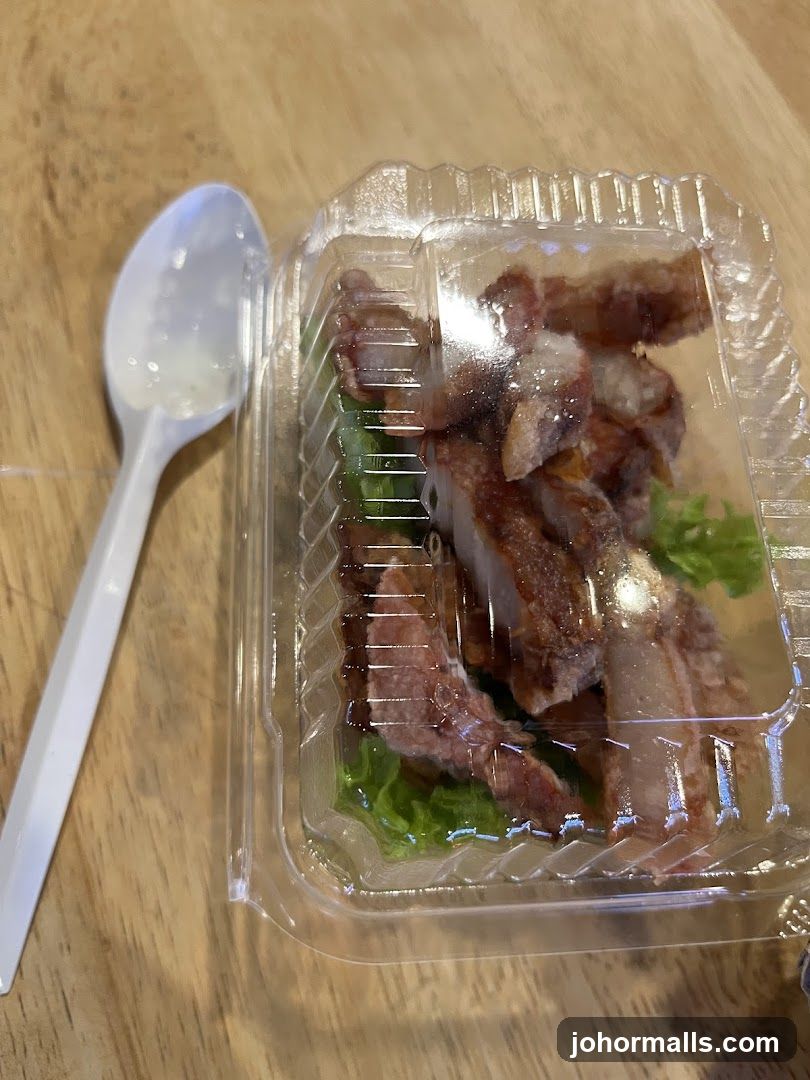 To-go container of meat and lettuce with a plastic spoon