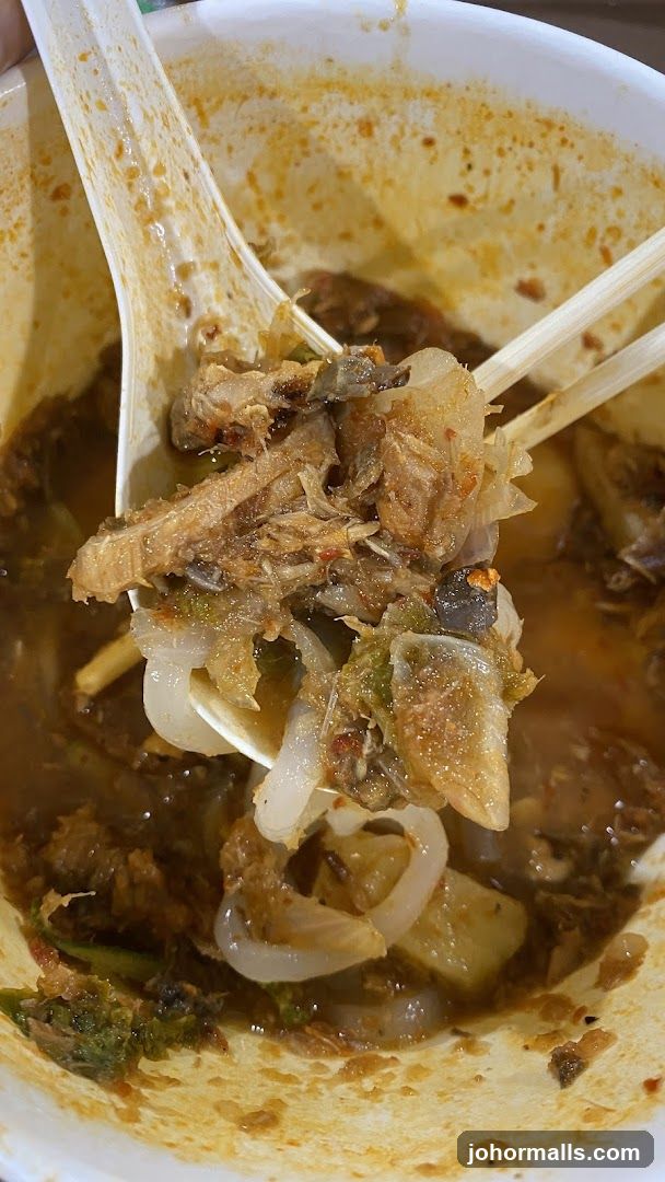 Close-up of a bowl of noodles with shredded meat and broth