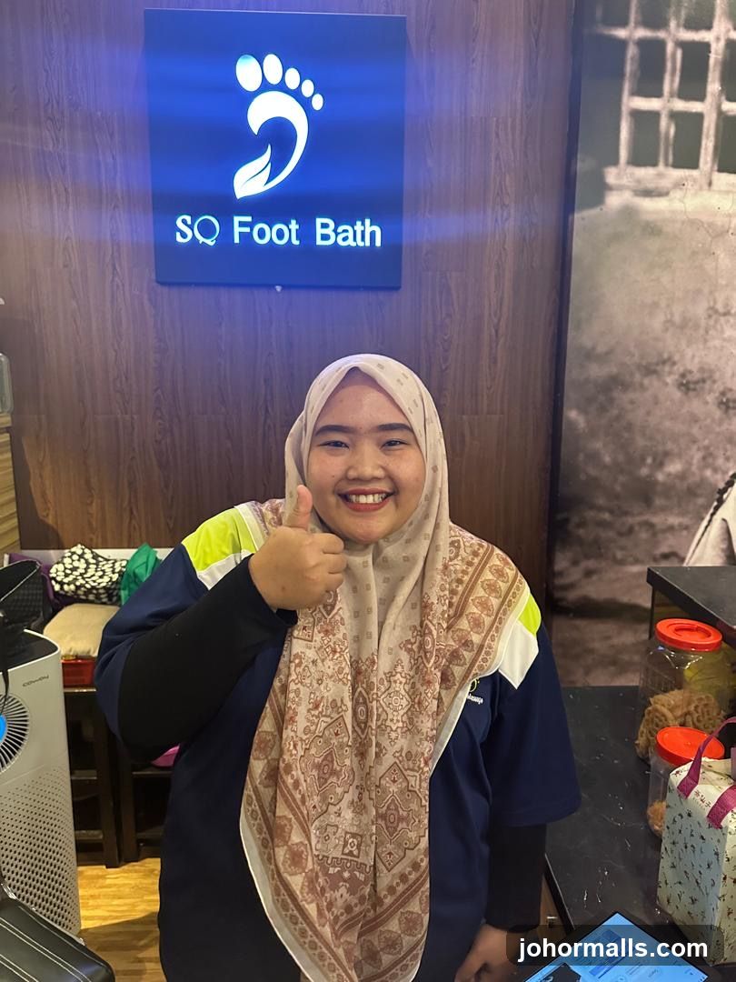 Woman giving a thumbs up in front of a sign