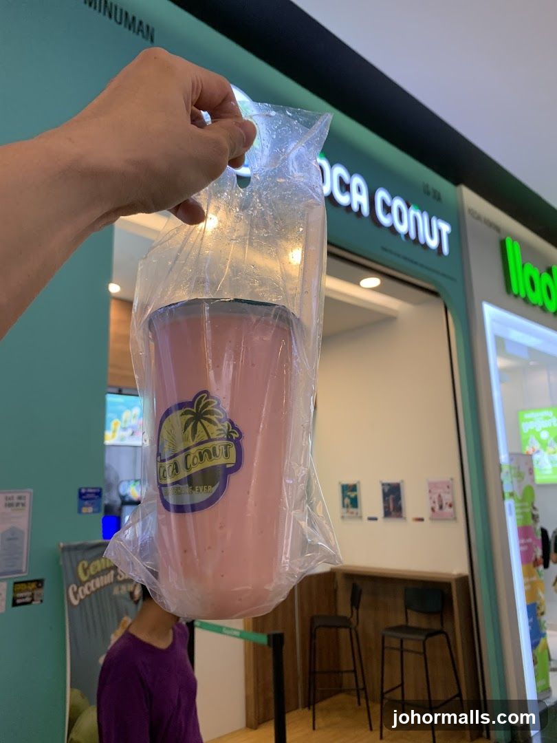 Person holding a pink beverage outside a shop