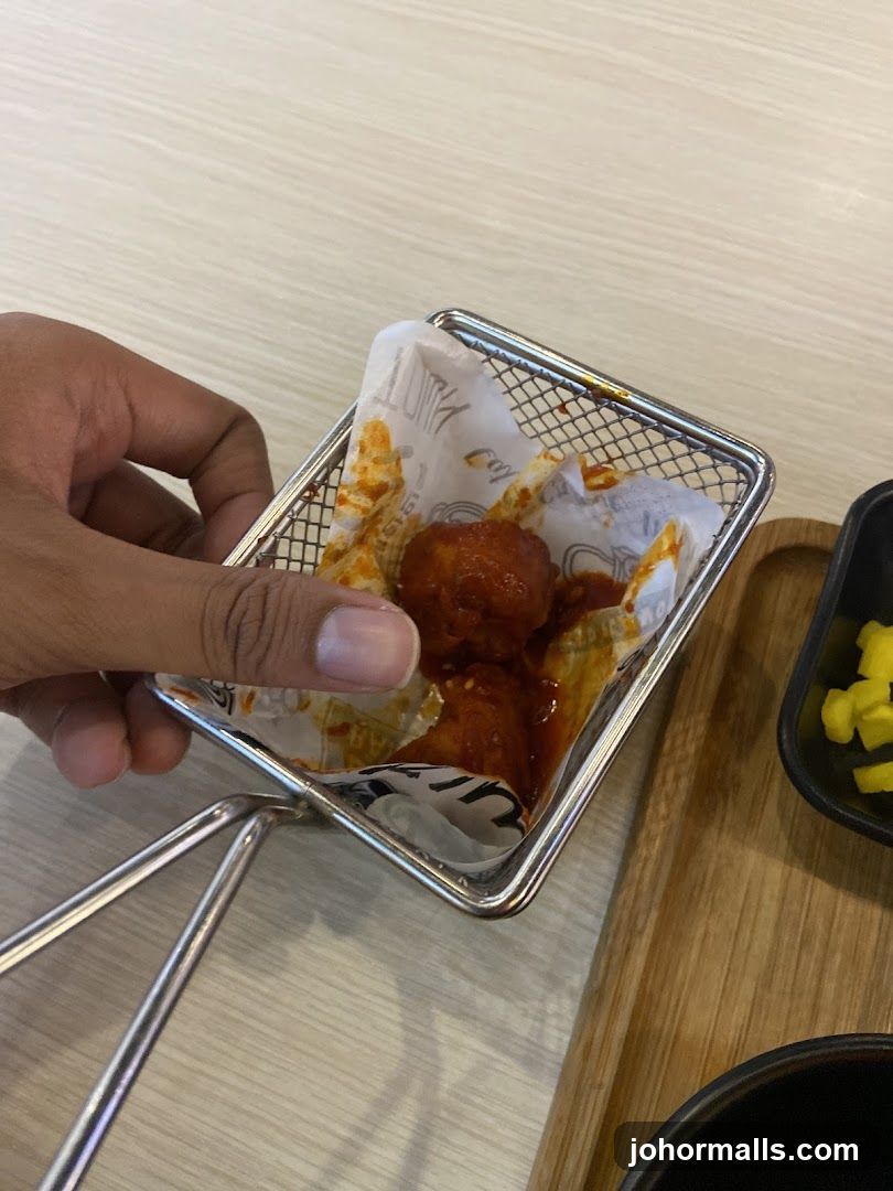Hand holding fried chicken in a metal basket